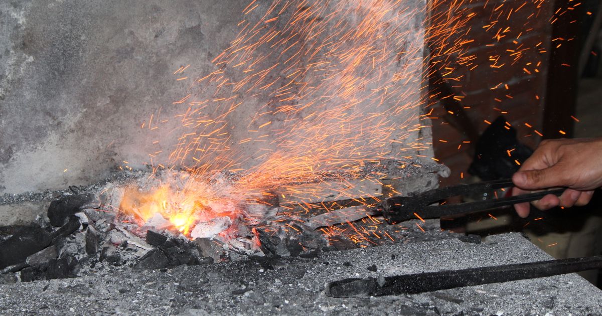 Close inspection of a hot refractory face with tongs, illustrating the kind of close-access visual and thermal check a boiler refractory inspection requires