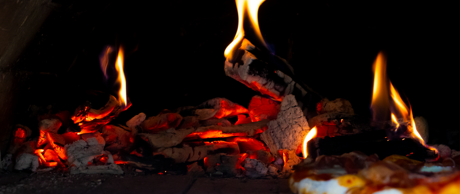 Close-up of a warm fireplace with flickering flames — the firebrick lining visible behind the fire handles direct flame exposure that would destroy common brick