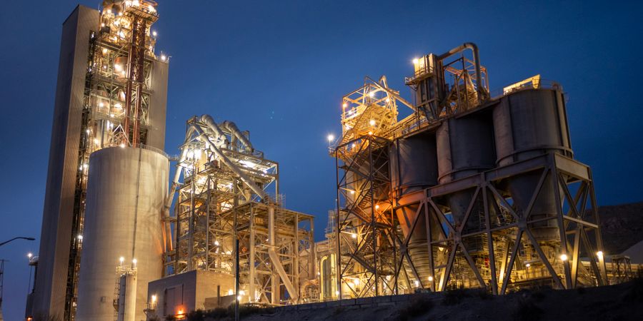 Night view of an illuminated cement plant, showing the continuous industrial operation that depends on reliable kiln refractory lining