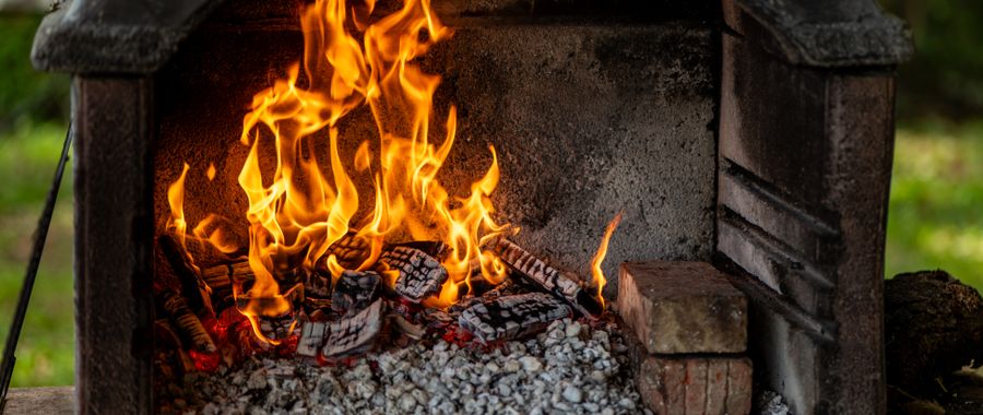 Outdoor brick fireplace with open flames showing where common brick and fire brick face very different thermal demands