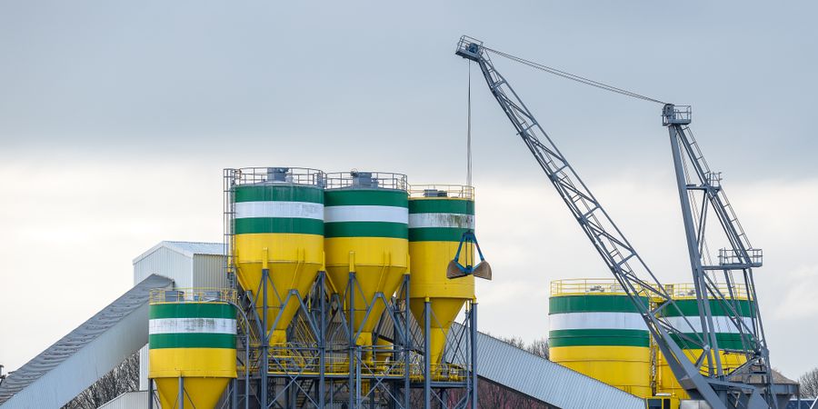 Large industrial cement plant silos and cranes, representing the scale of operations that depend on correct kiln refractory brick selection