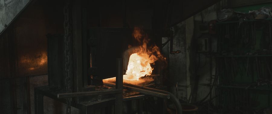 Industrial forge with glowing flame showing the type of direct high heat where refractory fire brick is required