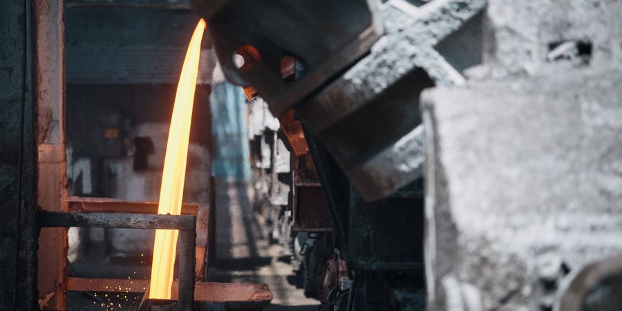 Molten steel pouring from a ladle in a steel mill — refractory bricks in the ladle and converter must resist both the heat and the basic slag chemistry