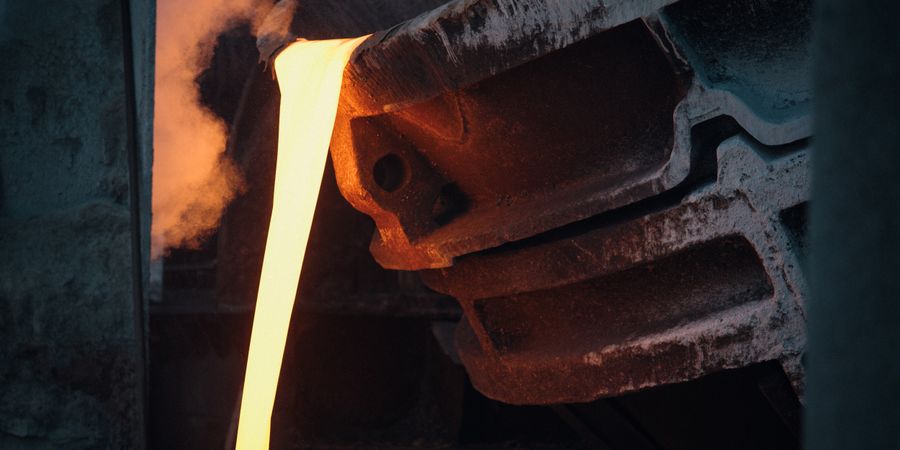 Molten metal pouring from a steel ladle in an active foundry — the interior lining must resist basic slag chemistry and temperatures exceeding 1,650°C